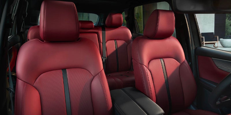 The interior of a car with red leather seats, showing textured black stripes down the center and black headrests.