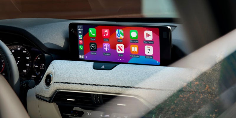 In-car infotainment screen displaying phone, music, maps, messages, podcasts, news, audiobooks, and calendar apps.